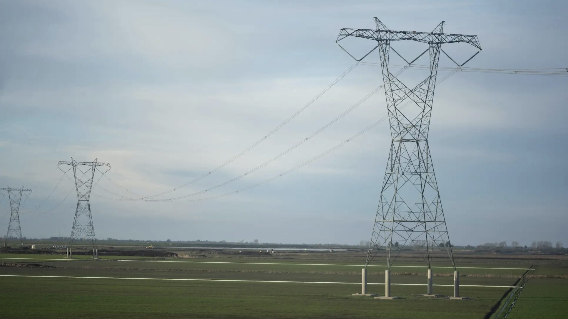 Row of electricity pylons in green field